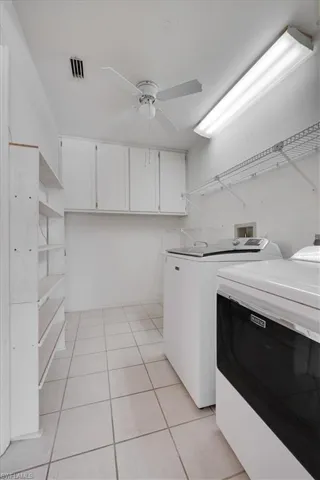 Laundry room with cabinets, ceiling fan, light tile patterned floors, and independent washer and dryer