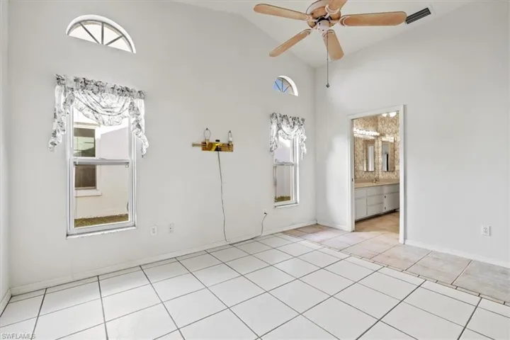 Bedroom with light tile patterned floors, high vaulted ceiling, and ceiling fan