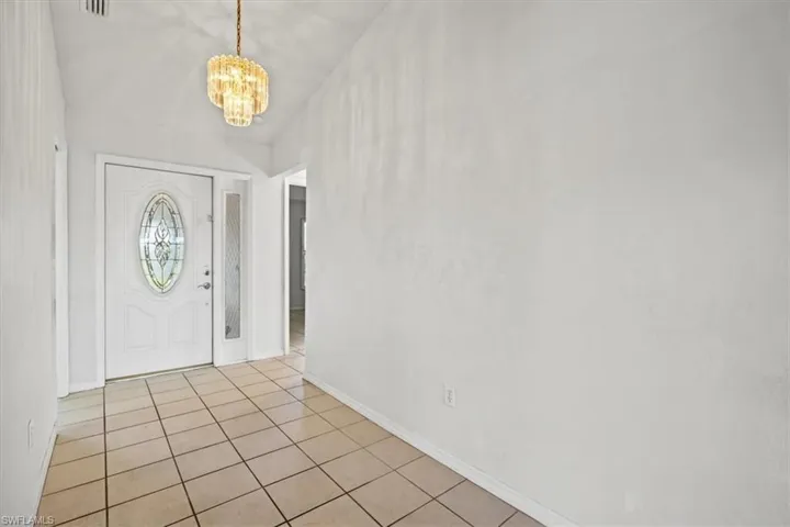 Entrance foyer with a chandelier and light tile patterned flooring
