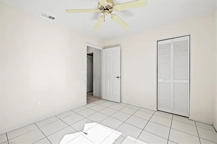 Unfurnished bedroom with light tile patterned flooring, ceiling fan, and a closet