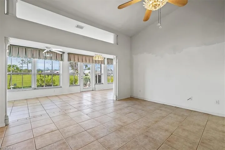 Unfurnished room featuring lofted ceiling, light tile patterned floors, and ceiling fan