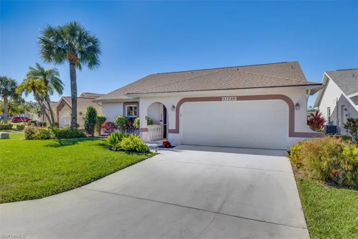 View of front of house with central AC unit, a garage, and a front yard