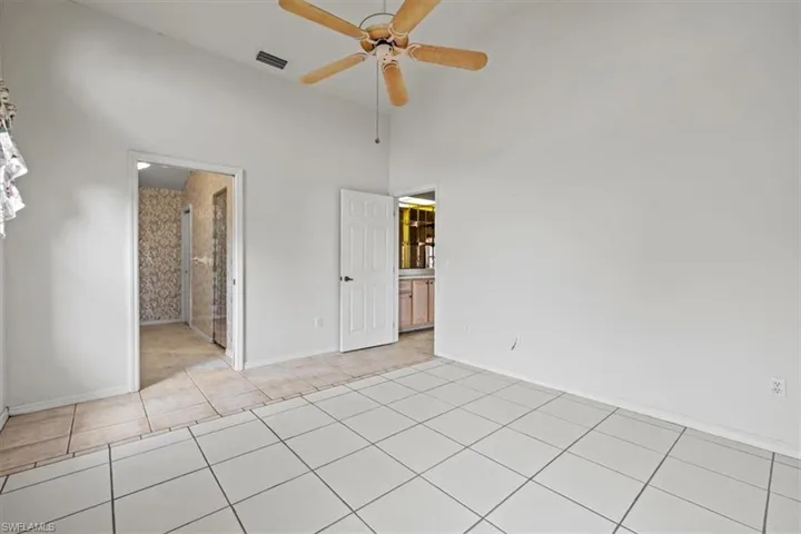 bedroom featuring ceiling fan, a high ceiling, and light tile patterned floors