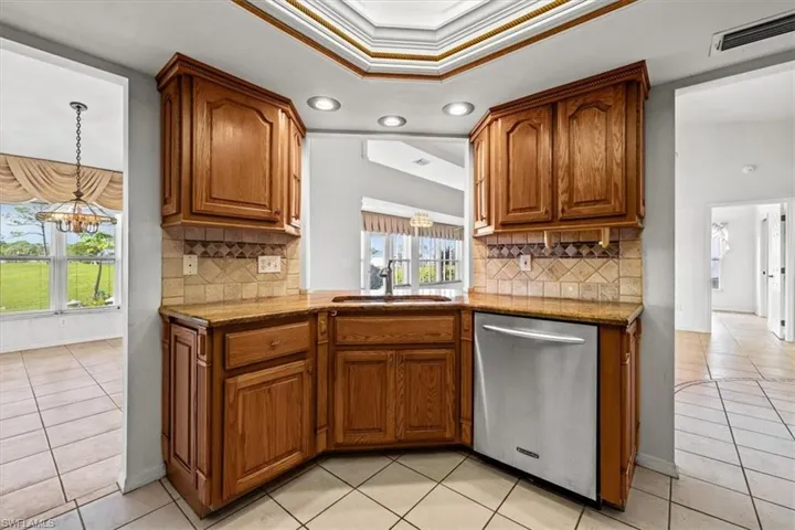 Kitchen with tasteful backsplash, crown molding, sink, and stainless steel dishwasher