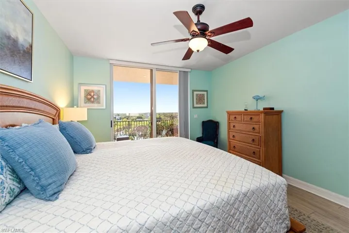 Bedroom featuring access to outside, wood finished floors, a ceiling fan, and floor to ceiling windows