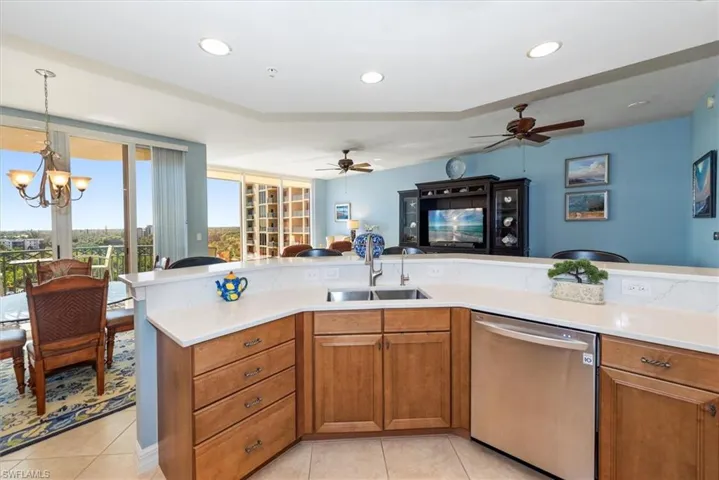 Kitchen featuring wood finish cabinets, open floor plan, dishwasher, hanging lights, and light tile patterned flooring