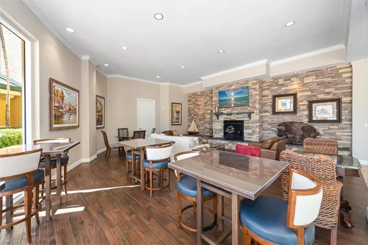 Dining area with dark wood finished floors, a fireplace, crown molding, an accent wall, and recessed lighting
