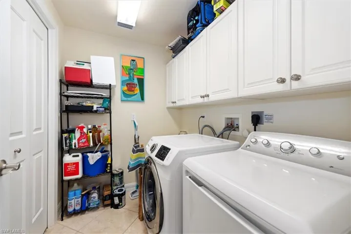 Laundry room with cabinet space, washing machine and dryer, and light tile patterned flooring
