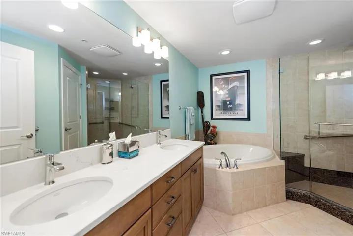 Bathroom featuring a shower stall, double vanity, a bath, light tile patterned floors, and recessed lighting
