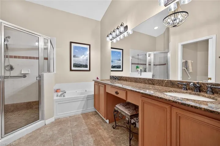 Bathroom with double vanity, a shower stall, a garden tub, and light tile patterned floors