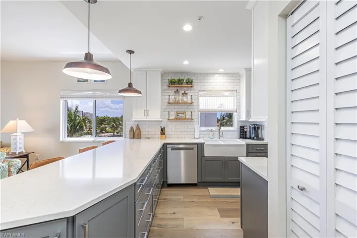 Kitchen featuring a peninsula, dishwasher, light wood-style flooring, decorative backsplash, and gray cabinetry