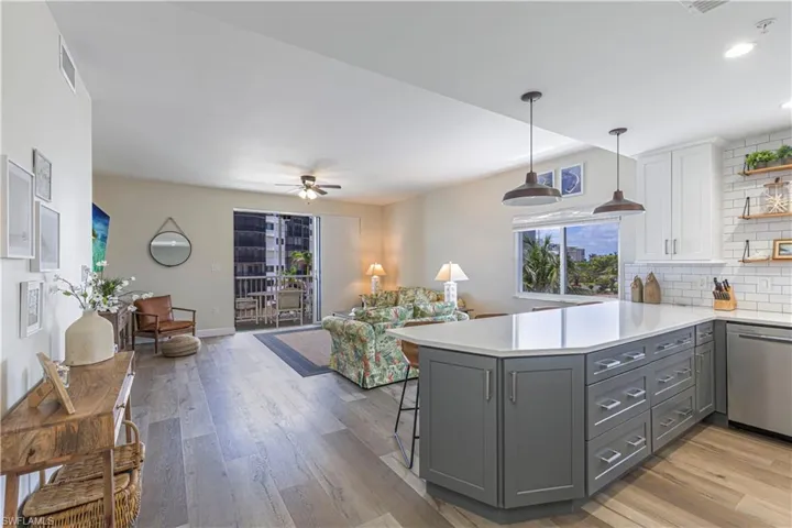 Kitchen with a peninsula, visible vents, light countertops, stainless steel dishwasher, and gray cabinetry