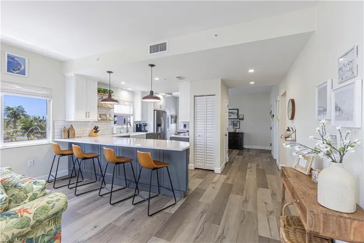 Kitchen with visible vents, white cabinetry, a peninsula, stainless steel fridge, and light countertops