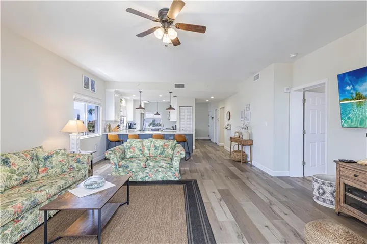 Living room featuring baseboards, light wood finished floors, ceiling fan, and visible vents