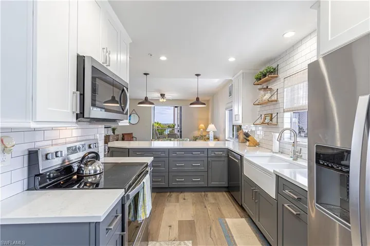 Kitchen featuring light wood finished floors, a sink, stainless steel appliances, backsplash, and gray cabinetry