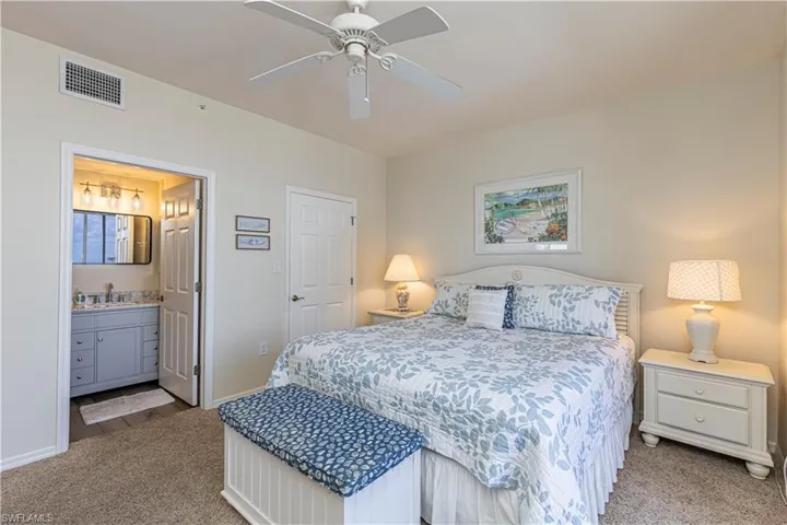 Carpeted bedroom with ensuite bathroom, visible vents, baseboards, and a sink