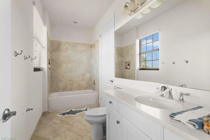 Full bathroom featuring tile patterned flooring, vanity, tiled shower / bath combo, and toilet