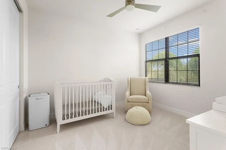 Bedroom with ceiling fan, a closet, a nursery area, and light carpet
