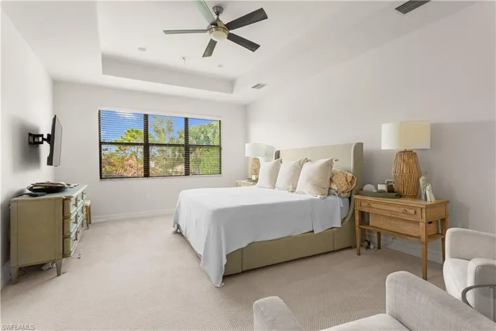 Carpeted bedroom featuring a tray ceiling and ceiling fan