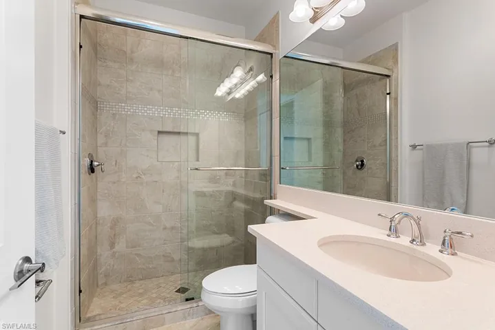 Bathroom featuring vanity, toilet, and a shower with shower door