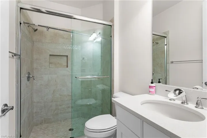 Bathroom featuring vanity, an enclosed shower, and toilet