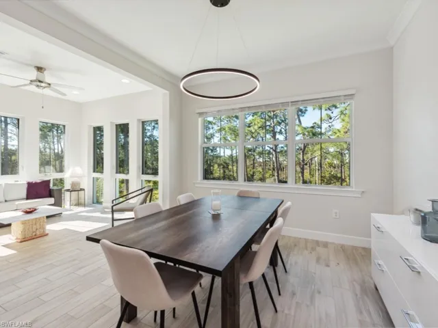 Dining room with light wood-style flooring, ceiling fan, and crown molding