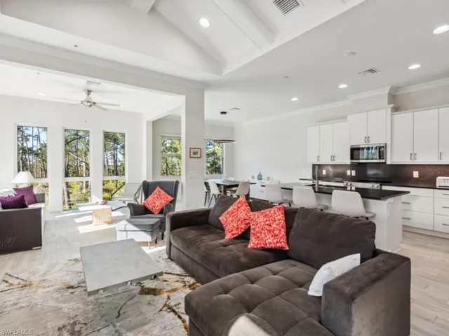 Living room with lofted ceiling with beams, ceiling fan, and light wood-type flooring