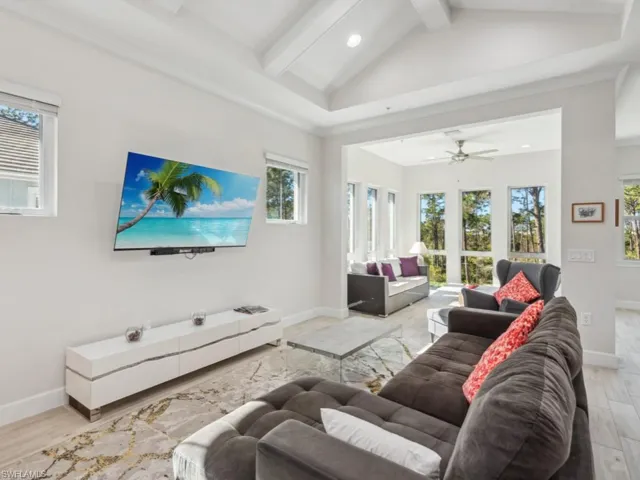 Living room with beam ceiling, light wood-type flooring, high vaulted ceiling, and ceiling fan