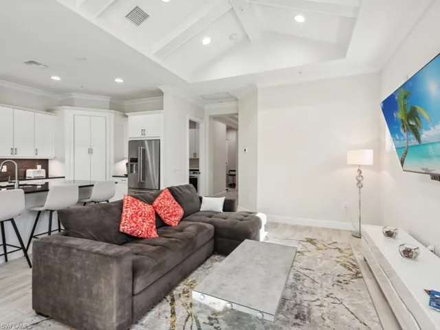 Living room with lofted ceiling, light wood-style flooring, and crown molding
