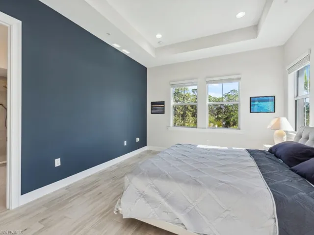 Bedroom with a raised ceiling and light hardwood / wood-style flooring