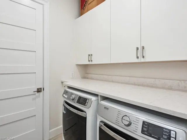 Laundry room with washing machine and dryer, cabinets, and wood-type flooring