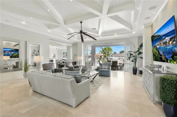 Living area with coffered ceiling, a ceiling fan, recessed lighting, and ornamental molding