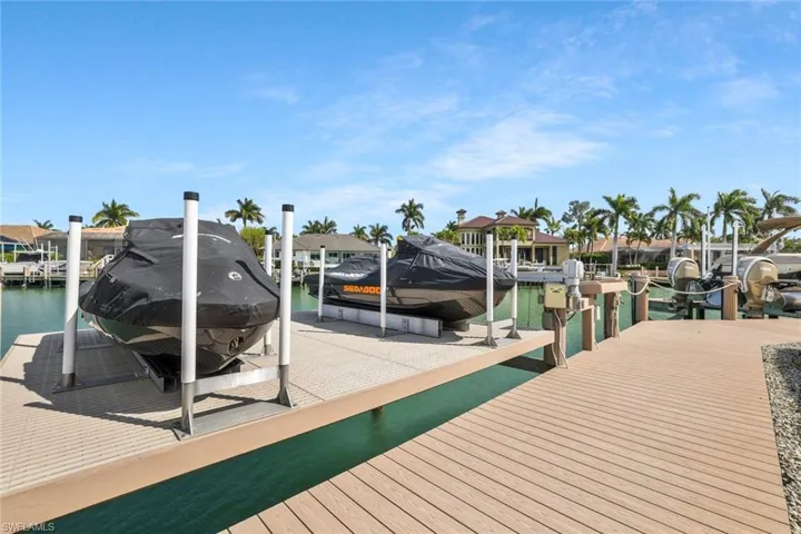 Dock featuring boat lift, a water view, and a residential view