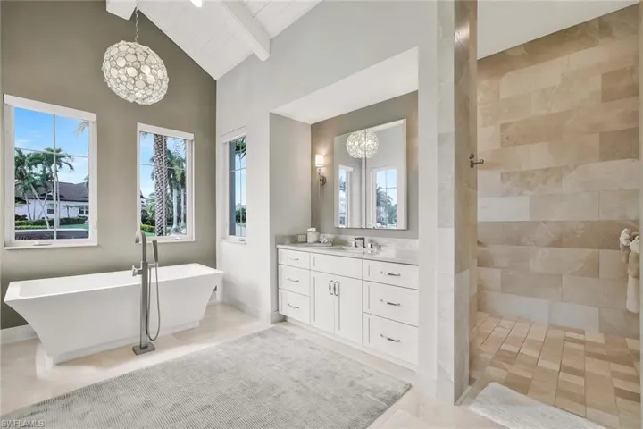 Bathroom with vanity, a chandelier, a freestanding tub, walk in shower, and a high wood beamed ceiling