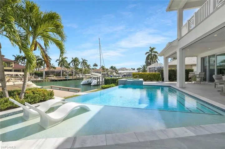 Integrated pool / spa featuring a patio area, a balcony, and a water view