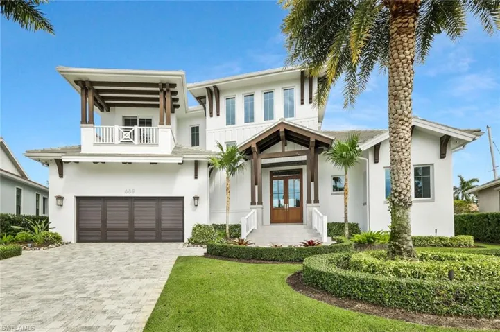 View of front facade featuring french doors, an attached garage, driveway, and stucco siding