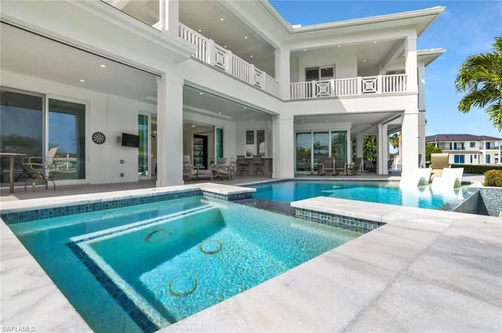 Back of house with a patio, outdoor dining area, a pool with connected hot tub, a balcony, and stucco siding