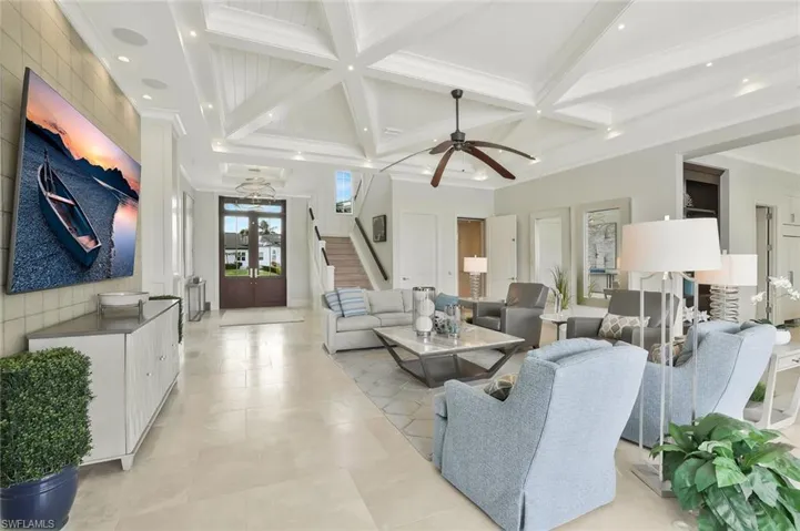 Living room with coffered ceiling, ornamental molding, and ceiling fan