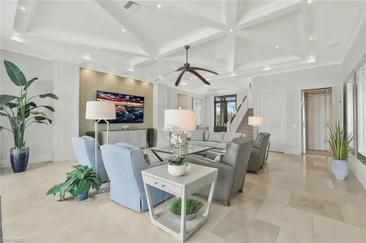 Living room featuring coffered ceiling, an accent wall, recessed lighting, ceiling fan, and crown molding