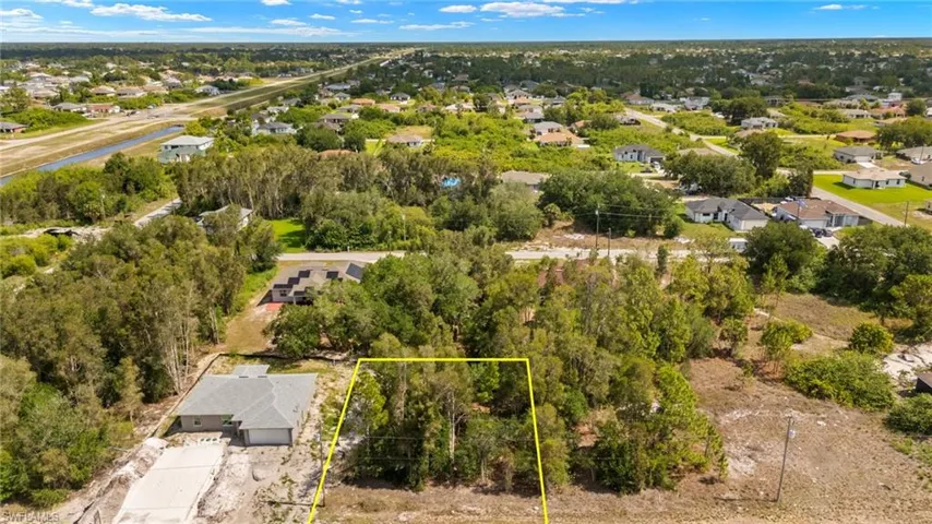 Aerial view of residential area featuring property boundaries highlighted and a tree filled landscape