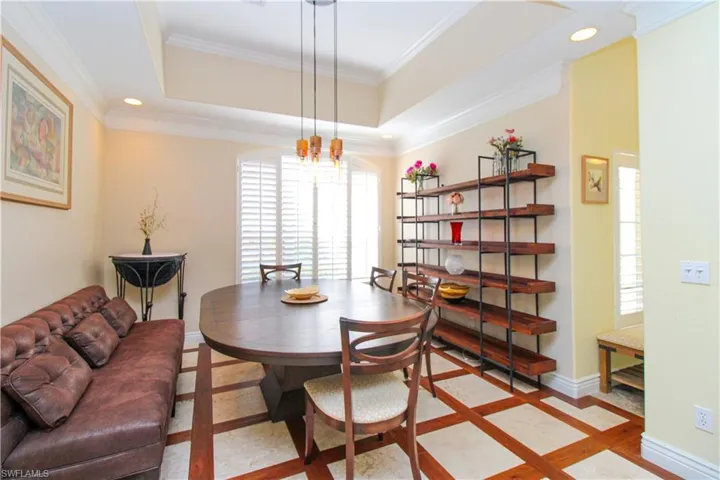 Dining space with a raised ceiling, an inviting chandelier, and ornamental molding