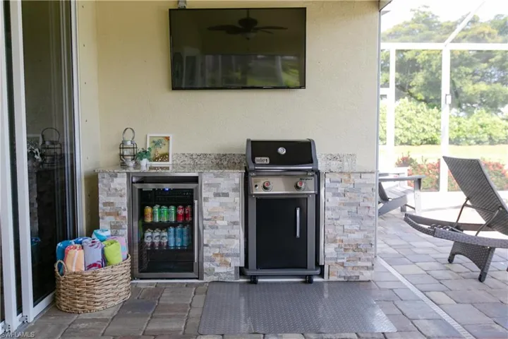 View of terrace featuring ceiling fan, area for grilling, beverage cooler, an outdoor kitchen, and a lanai