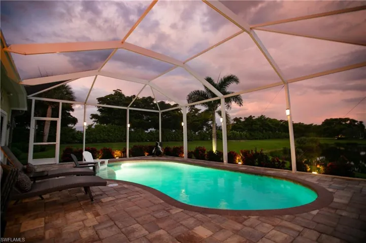 Pool at dusk with a patio and a lanai