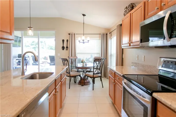 Kitchen with stainless steel appliances, sink, light tile floors, and pendant lighting