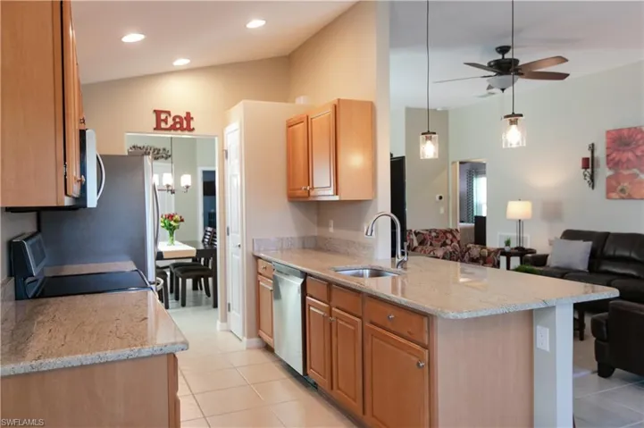 Kitchen featuring light tile floors, sink, light stone counters, and stainless steel appliances