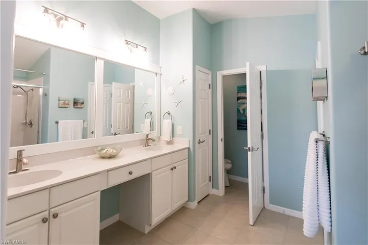 Bathroom with double sink vanity, toilet, and tile floors