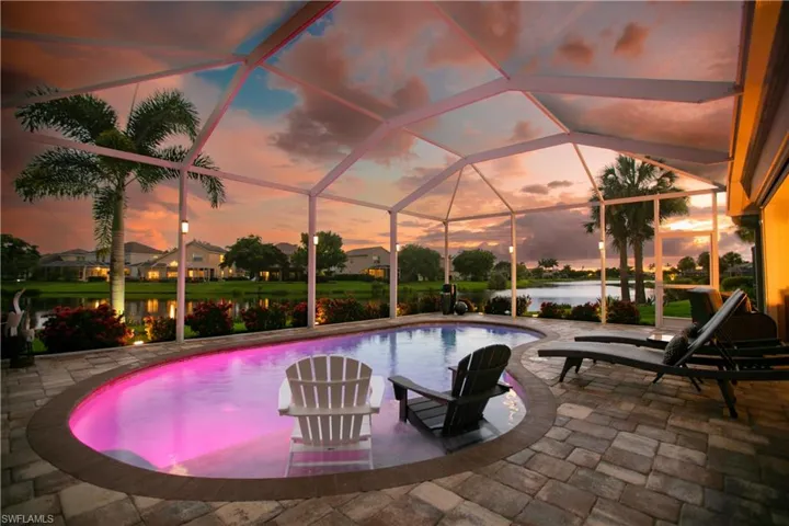 View of swimming pool with a water view, glass enclosure, and a patio area