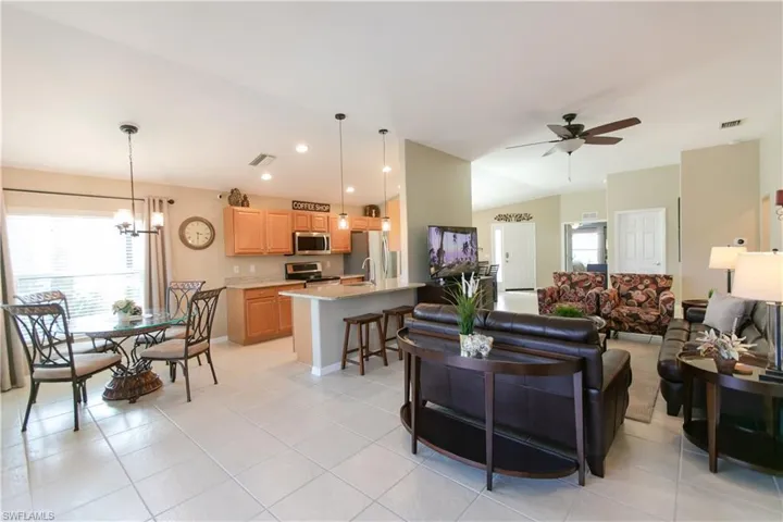 Tiled living room featuring sink and ceiling fan with notable chandelier