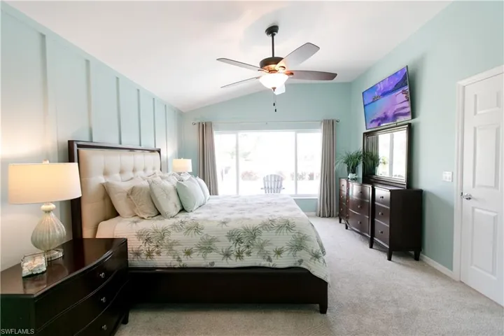 Bedroom featuring ceiling fan, light colored carpet, and lofted ceiling