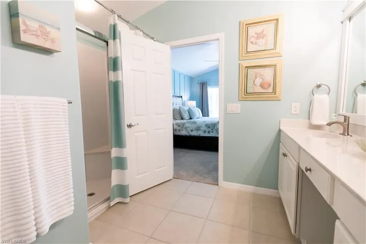 Bathroom with a shower with shower curtain, tile flooring, vaulted ceiling, and vanity